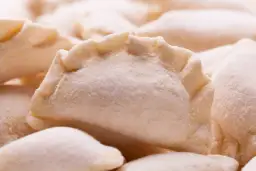Zamrożone pierogi ułożone blisko siebie, pokryte szronem.