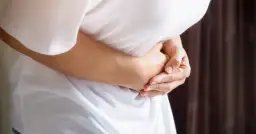 Osoba trzyma się za brzuch, odczuwając ostry ból w lewym boku.