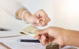 Dwie ręce: jedna podaje złoty pierścionek z brylantem, druga odbiera plik banknotów euro. Tak działa lombard.