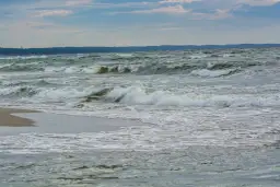 Fale rozbijają się o brzeg. Zastanawiasz się, co robić zimą nad morzem? Spacer po plaży i podziwianie żywiołu to świetny pomysł.