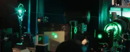 Eksperyment fizyczny z zielonymi laserami i optyką w ciemnym laboratorium.