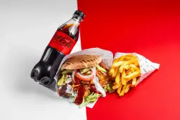 Duży kebab z frytkami i butelką Coca-Coli Zero na czerwono-białym tle.