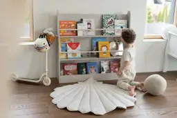 Chłopiec wybiera książkę z regału, tworząc przytulną przestrzeń do nauki i zabawy. Idealne miejsce na montessori w domu.