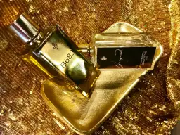 Dwa flakony perfum Marc Antoine Barrois, jeden z napisem B683, drugi z Ganymede, na złotej, cekinowej tkaninie.