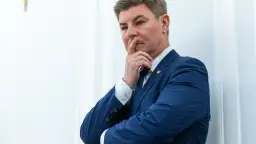 Jan Grabiec w garniturze, zamyślony, z palcem przy ustach. Może myśli o przyszłości dzieci?