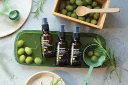 Butelki ze skwalanem z oliwek, otoczone świeżymi oliwkami i gałązkami rozmarynu, sugerują naturalne pochodzenie produktu.