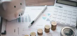 Świnka skarbonka, stosy monet, kalkulator i wykresy symbolizują finanse i rachunkowość.