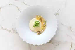 Dessert crémeux avec spirale verte, garni de fruits confits et graines.