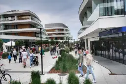 Spacer po nowoczesnej promenadzie w Świnoujściu, gdzie liczne atrakcje czekają na turystów. Ludzie spacerują, sklepy i apartamenty zachwycają architekturą.