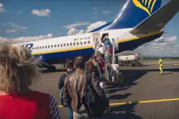 Ludzie wchodzą po schodkach do samolotu Ryanair. Czas na odprawę!