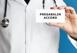 Lekarz w białym kitlu trzyma kartkę z napisem PREGABALIN ACCORD. Stetoskop wisi na jego szyi.