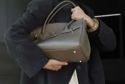 Elegancka, szara torebka na ramię z uchwytami i złotymi elementami. Idealnie wpisuje się w trendy, pokazując, jakie torebki są teraz modne.
