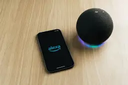 Telefon z logo Alexa i głośnik Echo na drewnianym blacie. Chcesz wiedzieć, alexa co to?
