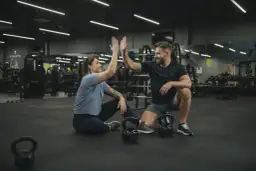 Para, którzy szukają crossfit Wrocław, gdzie można poczuć energię i wsparcie. Para świętuje sukces na siłowni.