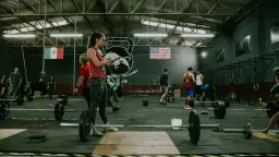 Ludzie ćwiczący CrossFit w siłowni z ciężarami i flagami Meksyku i USA.