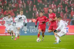 Piłkarze walczą o punkty, które decydują, ile trzeba mieć punktów aby utrzymać się w ekstraklasie. W akcji zawodnicy w czerwonych i białych strojach.