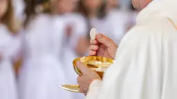 Ksiądz trzymający hostię i kielich podczas komunii świętej.