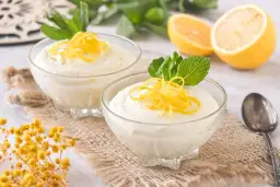 Dos copas de cremoso mousse de limón con leche condensada, decoradas con ralladura de limón y menta.