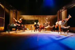 Aktorzy Teatru Lalek Pleciuga w dynamicznych pozach na scenie, unoszący się w powietrzu.