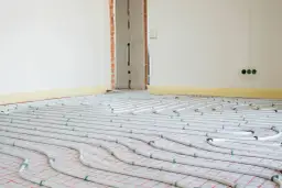 System ogrzewania podłogowego w trakcie montażu. Rury ułożone na siatce, gotowe do zalania betonem. To przyszłe oszczędności na koszt ogrzewania podłogowego.