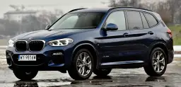 Ciemnoniebieskie BMW X3 na mokrej nawierzchni. Eleganckie linie i sportowy charakter tego SUV-a robią wrażenie.