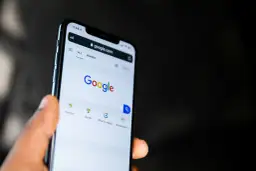 Dłoń trzyma smartfon z otwartą stroną Google. Widać pasek wyszukiwania i opcje takie jak pogoda, sport, filmy, restauracje, idealne do odkrywania treści w Google Discover.