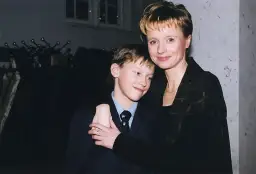 Uśmiechnięty Mateusz Matczak, syn Pieńkowskiej, w garniturze, przytulony do mamy.