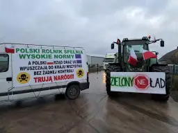 Ciężarówka i traktor z transparentami protestacyjnymi, polskie flagi, symbole czaszki i przekreślone "Zielony Ład".