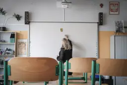 Nauczycielka pisze na tablicy interaktywnej w sali lekcyjnej.