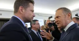 Czy Donald Tusk rzeczywiście obawia się ambicji prezydenckich Rafała Trzaskowskiego? Politycy rozmawiają w tłumie, w tle dziennikarze z aparatami.
