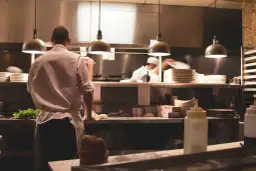 Kucharz w białej koszuli i fartuchu pracuje w kuchni restauracyjnej. To idealne miejsce, by napisać list motywacyjny kucharz.