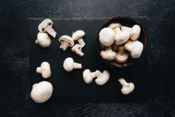 Świeże pieczarki na czarnej desce. Niskie pieczarki indeks glikemiczny sprawiają, że są idealne do zdrowej diety.