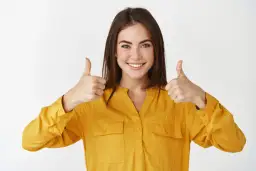 Uśmiechnięta kobieta w żółtej koszuli pokazuje kciuki w górę, symbolizując sukces w **referral marketing**.