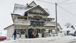 Drewniana restauracja "Schronisko Smaków" w Bukowinie Tatrzańskiej, pokryta śniegiem, z neonem "Restauracja".