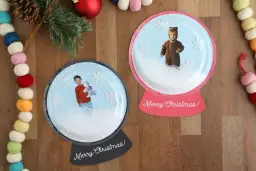 Dwie personalizowane kule śnieżne ze zdjęciami dzieci i płatkami śniegu.