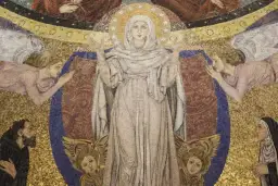 Wielobarwna mozaika przedstawia Matkę Boską otoczoną przez anioły i wiernych, symbolizującą kult maryjny.