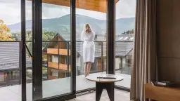 Kobieta w szlafroku podziwia widok na góry z tarasu hotelu Tremonti Karpacz.