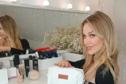 Blondynka z kosmetykami, szuka inspiracji, czym pomalować twarz na biało.