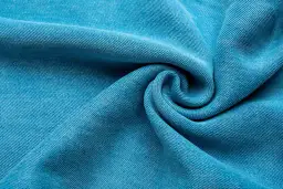 Textura de tela Tencel azul vibrante, suave y con caída, que evoca la comodidad y sostenibilidad de este tejido.
