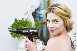 Kobieta z blond włosami trzyma czarną suszarkę do włosów Valera.
