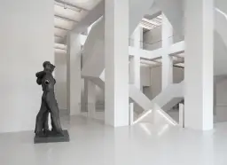 Rzeźba w nowoczesnym muzeum z betonową architekturą i schodami.