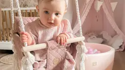 Urocza huśtawka dla niemowlaka w pastelowym różu, idealna do pokoju dziecięcego.