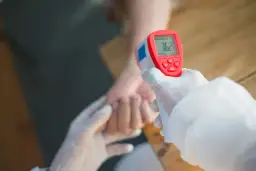 Rękawiczki i termometr bezdotykowy mierzą temperaturę, która może wskazywać na przewlekły stan podgorączkowy i zmęczenie.