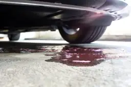 Plama pod samochodem. Czy płyn chłodniczy się zużywa? Czerwony wyciek na betonie.