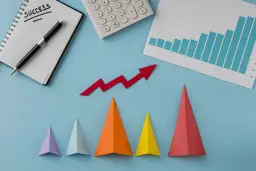 Notatnik z napisem "SUCCESS", kalkulator, wykres słupkowy i czerwona strzałka w górę symbolizują udany marketing performance.