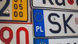 Zbliżenie na tablice rejestracyjne, w tym polskie z symbolem UE i oznaczeniem "PL", a także fragmenty innych tablic.