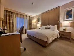 Komfortowy pokój hotelowy, idealny po długim locie tureckimi liniami lotniczymi. Duże łóżko, biurko i przytulne oświetlenie.