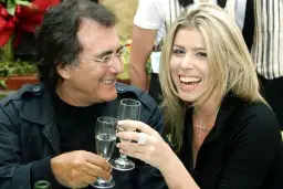 Al Bano i jego nowa partnerka, uśmiechnięci, wznoszą toasty kieliszkami szampana.