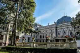 Majestatyczny pałac poznański z ozdobną balustradą i kwitnącymi kwiatami, otoczony zielenią.