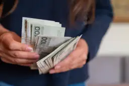 Dłonie liczą banknoty 100 zł. To może być darowizna od rodziców na nowy cel.